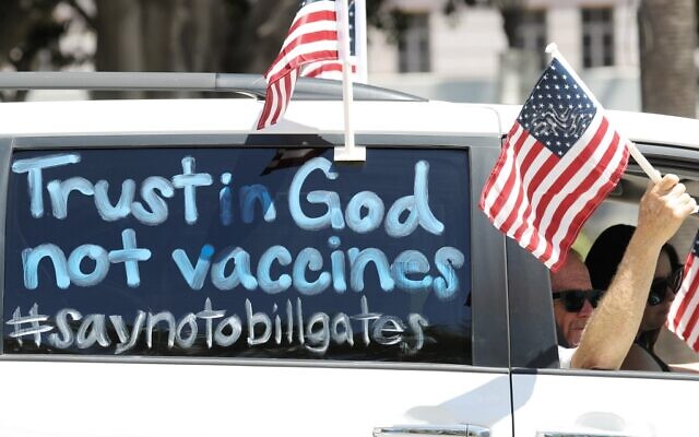 Demonstrators participate in a vehicle caravan with a sign reading 'Trust in God not vaccines' outside City Hall, on April 22, 2020, in Los Angeles, California. (Mario Tama/Getty Images/AFP)