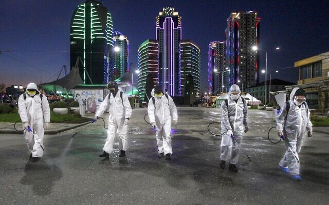 Municipal workers wearing protective suits spray disinfectant in an area in the center of Grozny, Russia, Monday, April 6, 2020. Ramzan Kadyrov, strongman leader of Russia's province of Chechnya, has taken extreme measures to fight the spread of the new coronavirus in the region, vowing Monday not to let anyone who is not a formal resident of Chechnya into the area. (AP Photo/Musa Sadulayev)