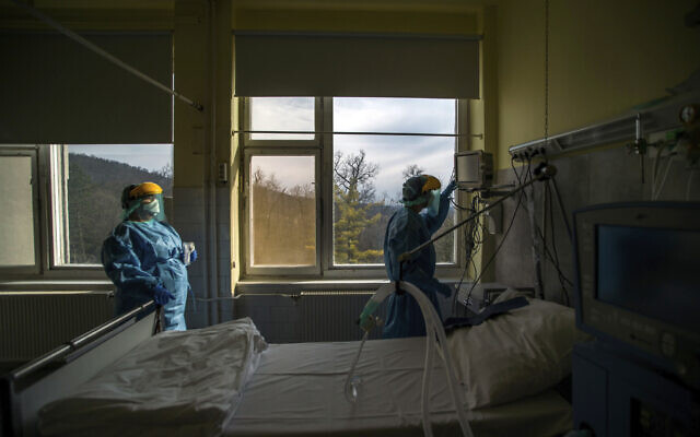 In this March 24, 2020, file photo, medical staff members check a ventilator in protective suits at the care unit for the new COVID-19 infected patients inside the Koranyi National Institute of Pulmonology in Budapest (Zoltan Balogh/MTI via AP, File)
