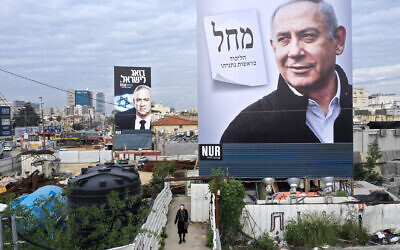 Election campaign billboards for Likud and its leader Prime Minister Benjamin Netanyahu (foreground), and the Blue and White party led by Benny Gantz (background), in Bnei Brak, February 23, 2020. (AP Photo/Oded Balilty)