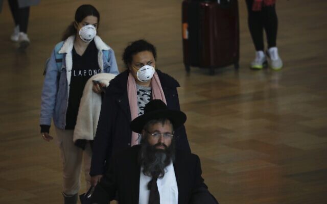 Passengers wearing masks to help protect against coronavirus arrive at the Ben Gurion airport near Tel Aviv on March 10, 2020. (AP Photo/Ariel Schalit)