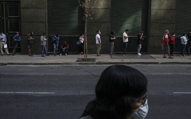 People wait in line to collect unemployment insurance, many of them affected by the economic crisis triggered by the spread of the new coronavirus, in downtown Chile on April 6, 2020. (AP/Esteban Felix)