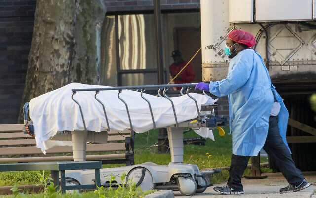 Medical personnel transport a body from a refrigerated container at Kingsbrook Jewish Medical Center, Wednesday, April 8, 2020, in the Brooklyn borough of New York (AP Photo/Mary Altaffer)