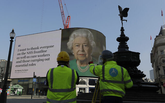 An image of Britain's Queen Elizabeth II and quotes from her historic television broadcast commenting on the coronavirus pandemic are displayed on a big screen behind the Eros statue at Piccadilly Circus in London, April 9, 2020. (AP Photo/Kirsty Wigglesworth)