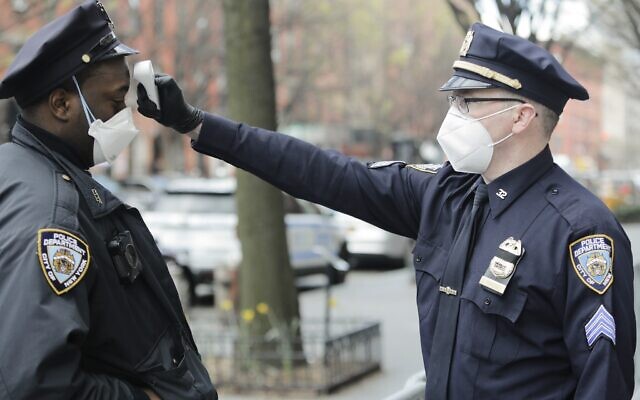Officer Mahoney, right, checks the temperature of all people entering the 32nd precinct of the New York Police Department in an attempt to stem the spread of the new coronavirus Wednesday, April 15, 2020, in New York. (AP Photo/Frank Franklin II)