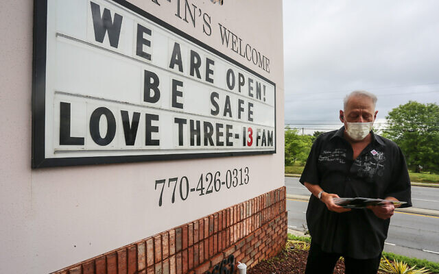 Lester Crowell, managing partner of Three-13 Salon & Boutique, changes the letters of the salon’s sign on Friday, April 24, 2020, in Marietta, Georgia (AP Photo/Ron Harris)