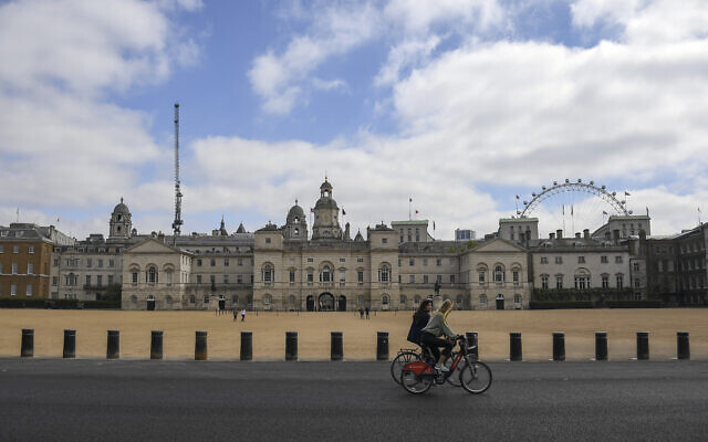 Two women ride bicycles past the Horse Guards Parade, during lockdown due to the coronavirus outbreak, in London, Saturday, April 25, 2020 (AP Photo/Alberto Pezzali)