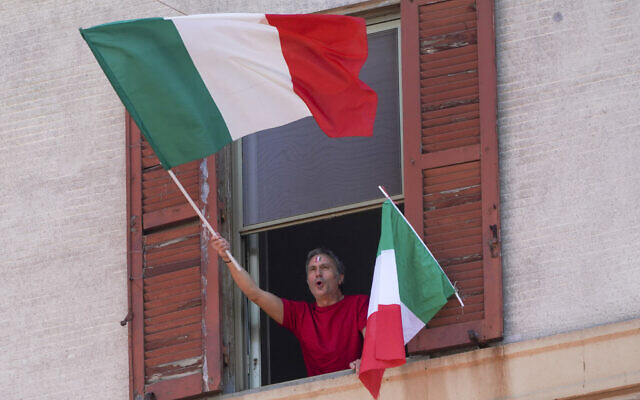 A man waves the Italian flag as he chants from his window on the occasion of the 75th anniversary of Italy’s Liberation Day, in Rome, Saturday, April 25, 2020 (AP Photo/Andrew Medichini)