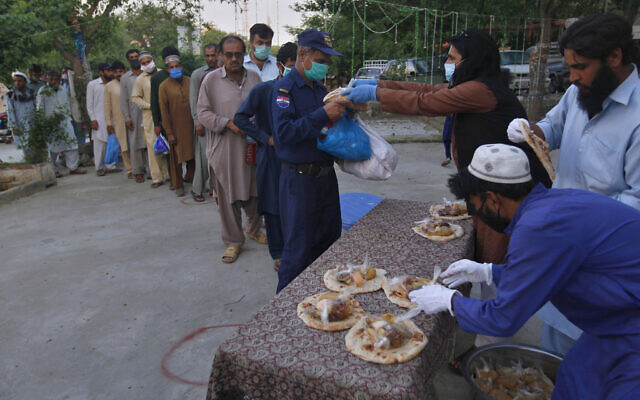 Volunteers distribute free food to daily wage workers and others for breaking their fast on the second day of Ramadan, in Islamabad, Pakistan. Sunday, April 26, 2020. (AP Photo/Anjum Naveed)