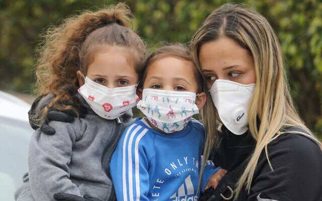 A family wear face masks to protect themselves from the coronavirus, March 18, 2020. (Yossi Aloni/Flash90)