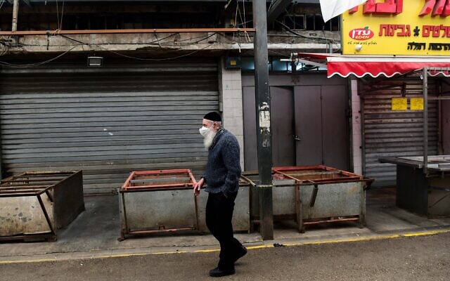 Illustrative: A man wearing a face mask walks through the empty market in Ramla, on March 23, 2020. (Flash90)