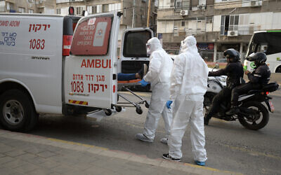 An illustrative photo of Magen David Adom paramedics transferring a man suspected of carrying the virus to an ambulance in the Tel Aviv suburb of Bnei Brak, March 31, 2020. (Gili Yaari/Flash90)