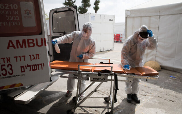 Magen David Adom workers cleaning an ambulance in Jerusalem on April 2, 2020. (Nati Shohat/Flash90)