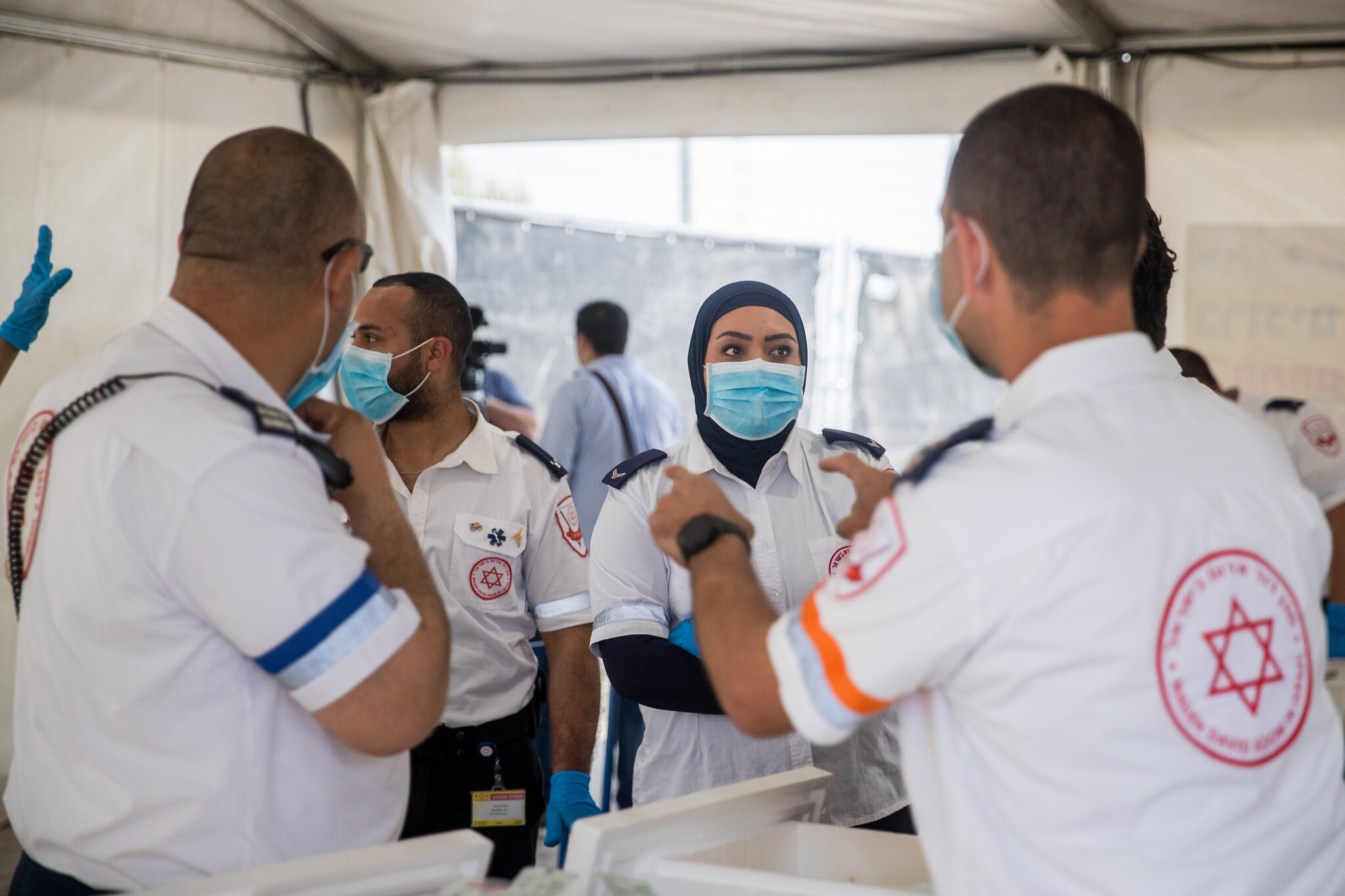 Magen David Adom medical workers seen at a drive-through site to collect samples for coronavirus testing, at the entrance to the East Jerusalem neighborhood of Jabel Mukaber, on April 2, 2020. (Yonatan Sindel/Flash90)