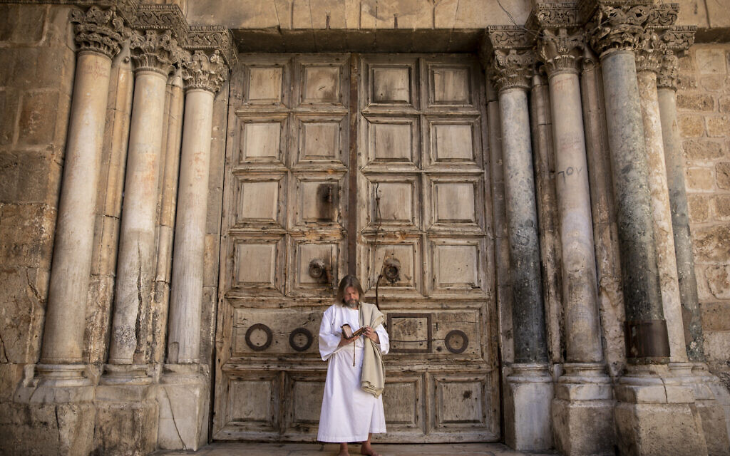 A Christian worshiper prays outside the  gates of the Holy Sepulchre Church in Jerusalem, which is closed in line with coronavirus regulations, April 04, 2020. (Olivier Fitoussi/Flash90)