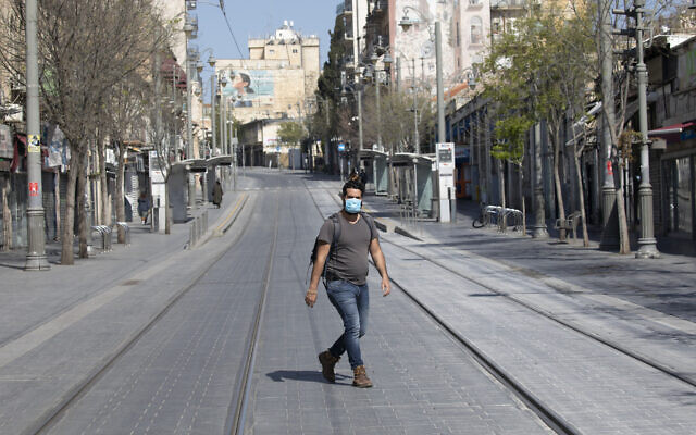 An Israeli man with a face mask walks in an empty street in Jerusalem on April 14, 2020 (Olivier Fitoussi/Flash90