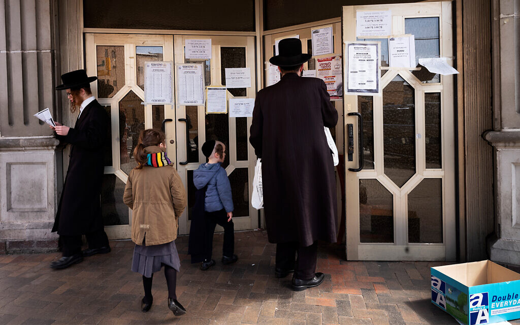 A man stops to read announcements posted on the doors of a synagogue in the Williamsburg neighborhood of Brooklyn, New York, April 7, 2020. (AP/Mark Lennihan)