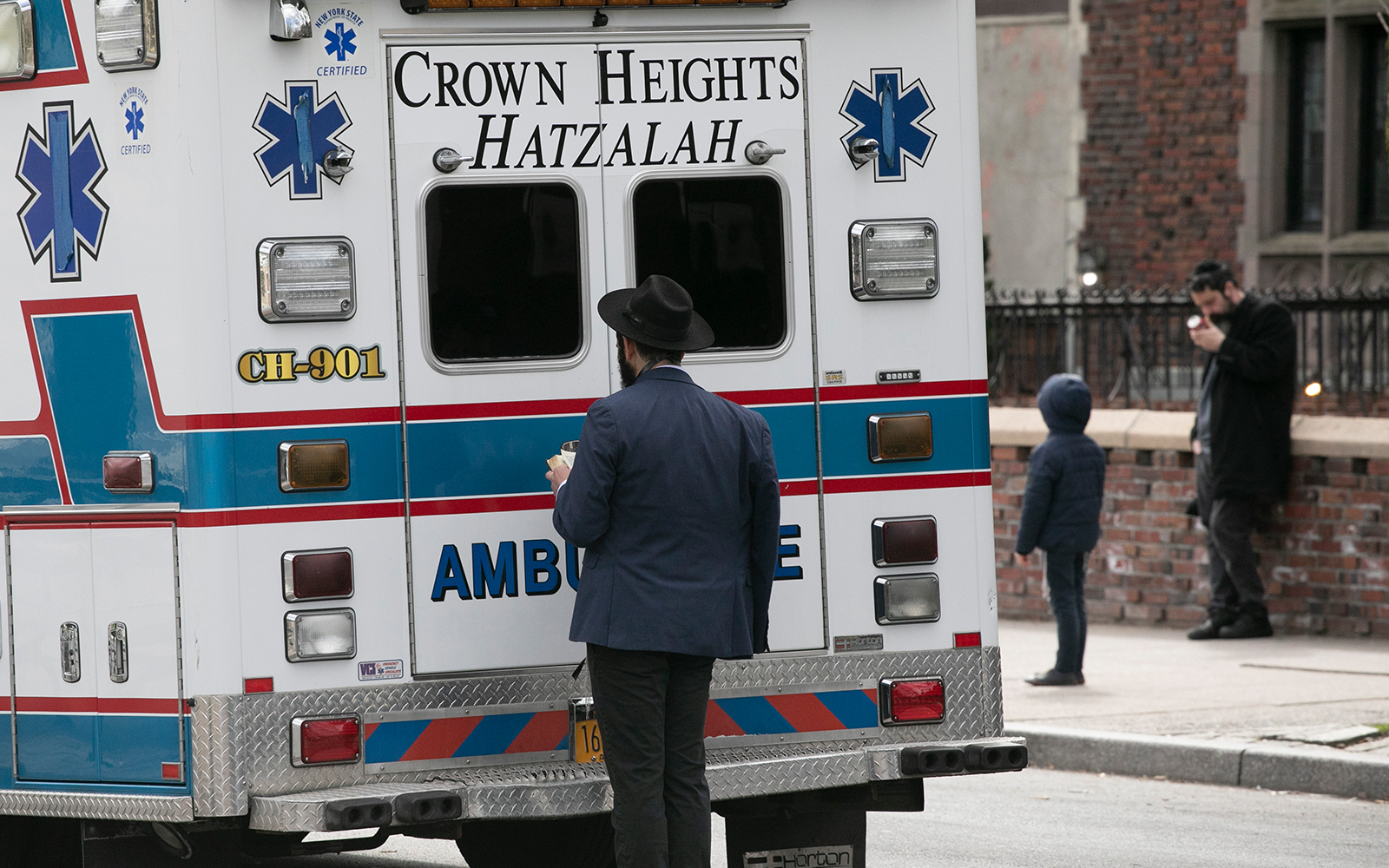 A man prays next to an idle ambulance in the Crown Heights neighborhood of Brooklyn, New York, April 7, 2020. (AP/Mark Lennihan)