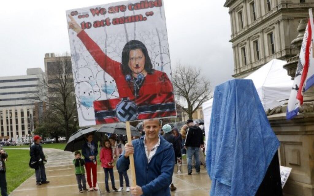 A protestor with a sign that has Michigan Gov. Gretchen Whittmer depicted as Adolph Hitler at an American Patriot Rally organized by Michigan United for Liberty protest for the reopening of businesses on the steps of the Michigan State Capitol in Lansing, Michigan, April 30, 2020. (Jeff Kowalsky/AFP)