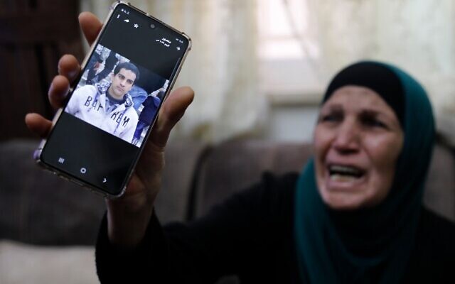 The mother of a Palestinian man with special needs, who police said was shot dead when they mistakenly thought he was armed with a pistol, cries as she shows his picture on her mobile telephone, at her home in East Jerusalem, on May 30, 2020. (Ahmad GHARABLI / AFP)