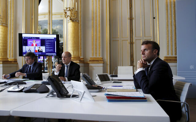 French President Emmanuel Macron, right, listens as he attends with French Foreign Minister Jean-Yves le Drian, center, an international videoconference on vaccination at the Elysee Palace in Paris, May 4, 2020. (Gonzalo Fuentes/Pool via AP)