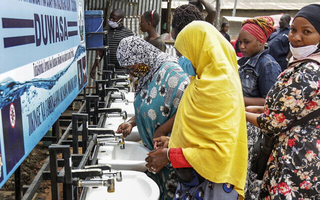 In this photo taken Monday, May 18, 2020, people use a hand-washing station installed for members of the public entering a market in Dodoma, Tanzania.  (AP Photo)