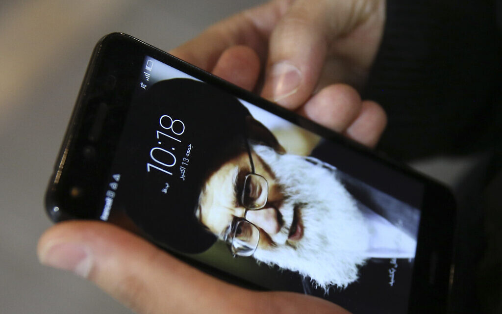 A Tehran resident, Hamed Ghassemi, looks at his cellphone, with a portrait of Iranian Supreme Leader Ayatollah Ali Khamenei. (AP Photo/Vahid Salemi)