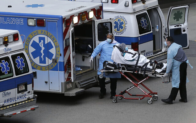 Medical personnel wearing personal protective equipment out of concern for the coronavirus remove a person from an ambulance near an entrance to Massachusetts General Hospital, in Boston, Monday, April 20, 2020. (AP Photo/Steven Senne)