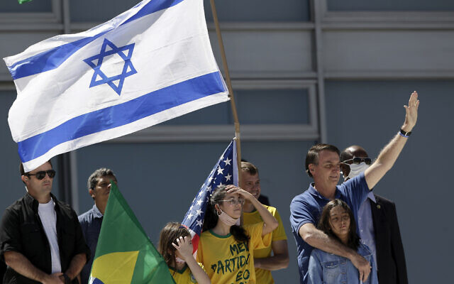 Brazil's President Jair Bolsonaro, right, embraces his daughter as supporters hold Israeli, American and Brazilian flags, during a protest against his former Minister of Justice Sergio Moro and the Supreme Court, in front of the Planalto presidential palace, in Brasilia, Brazil, Sunday, May 3, 2020. (AP Photo/Eraldo Peres)