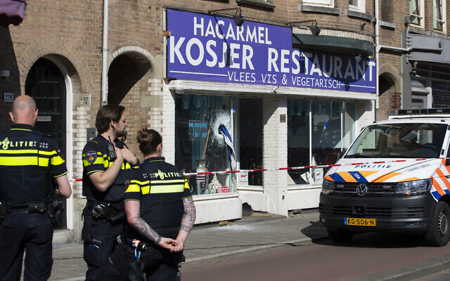 An Israeli flag sticks out of the window of HaCarmel kosher restaurant in Amsterdam, Netherlands, May 8, 2020, after a man smashed the window. (AP Photo/Peter Dejong)