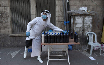 A Palestinian vendor with a mask displays his fresh fruit juice in the street as the markets remain partly closed, part of a lockdown and quarantine measures to protect residents from the coronavirus, in the West Bank city of Ramallah, May 19, 2020. (Nasser Nasser/AP)