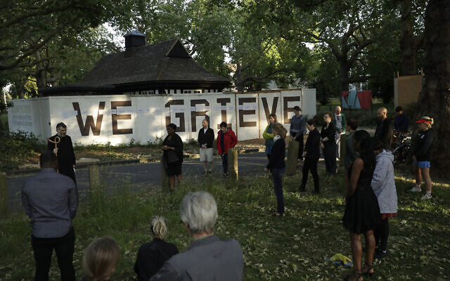 Reverend William Taylor, top left, and local people standing with social distancing observe a 30 second silence during a remembrance event as they add the names of five people who recently died to the community "We Grieve" wall at Clapton Common, in London, May 28, 2020 (AP Photo/Matt Dunham)