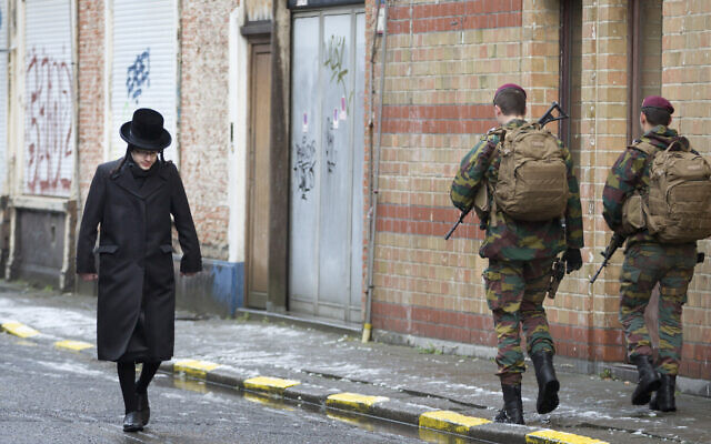 A Jewish boy walks past Belgian soldiers as they patrol during religious services in Antwerp, Belgium January 24, 2015. (AP Photo/Virginia Mayo)