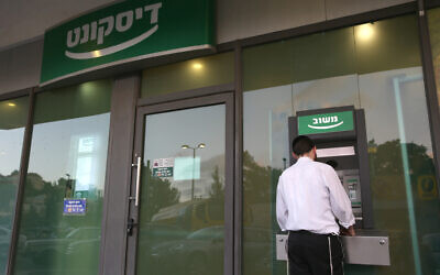 A man stands at a cash machine of the Israel Discount Bank in Jerusalem, on July 1, 2013. (Nati Shohat/Flash 90)