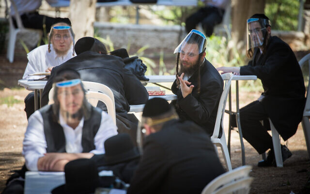 Ultra-Orthodox men, wearing face shields as a protective measure against the coronavirus, study in an outdoor area in Jerusalem on May 4, 2020. (Yonatan Sindel/Flash90)