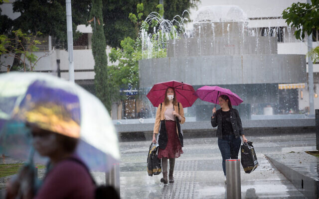 Israelis carry umbrellas on a rainy day in Tel Aviv. May 05, 2020. (Miriam Alster/FLASH90)
