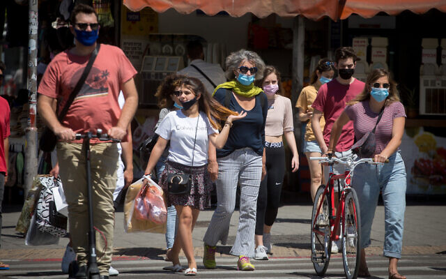 People wear protective face masks in Tel Aviv on May 8, 2020. (Miriam Alster/Flash90)