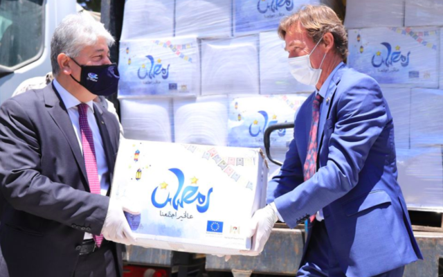 Illustrative: EU representative to the Palestinians Sven Kühn von Burgsdorff, right, hands more than 800 food packages to the PA's social development minister to be distributed to poor Palestinian families, April 30, 2020 (Facebook)