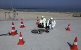 Technicians from Israeli firm Kando extract sewage samples from a manhole near the beach, in the southern coastal Israeli city of Ashkelon, on June 11, 2020 (Menahem Kahana/AFP)