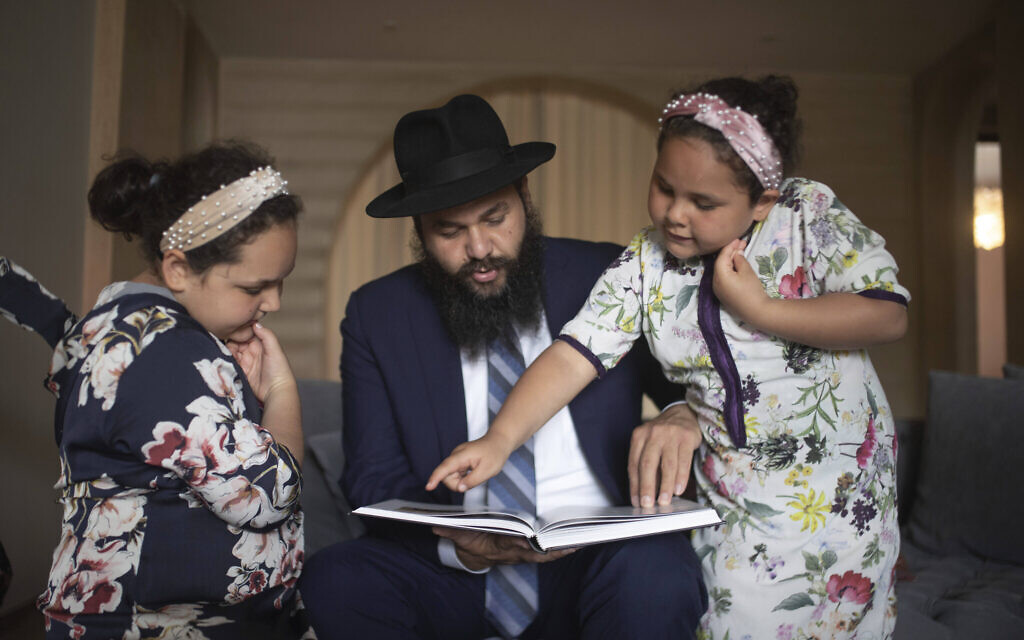 Rabbi Levi Banon and his daughters read a book inside their home in Casablanca, Morocco, May 28, 2020. (AP Photo/Mosa'ab Elshamy)