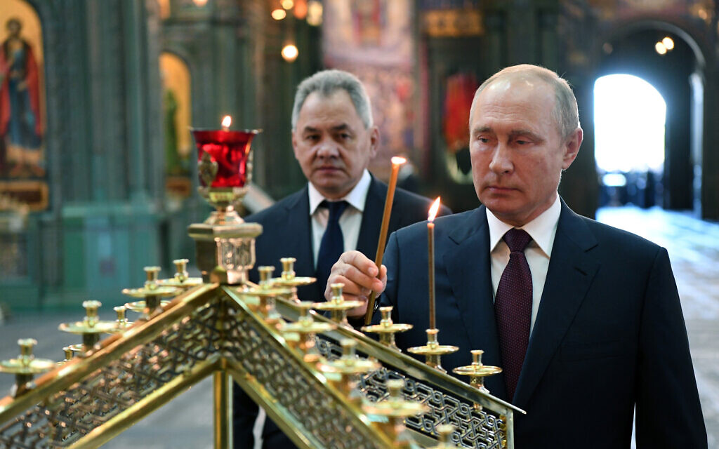 Russian President Vladimir Putin, right, lights a candle with Russian Defense Minister Sergei Shoigu in the background, at the Main Cathedral of the Russian Armed Forces, June 22, 2020. (Alexei Nikolsky, Sputnik, Kremlin Pool Photo via AP)