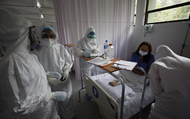 Medical staff wearing protective gear check on a patient in the women's ward of a COVID-19 hospital at Military Camp 1, Naucalpan, Mexico State, June 23, 2020. (AP Photo/Rebecca Blackwell)