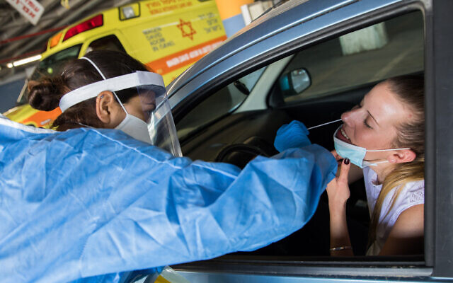 A medical worker at Shaare Zedek Medical Center in Jerusalem tests a woman for coronavirus on April 30, 2020. (Nati Shohat/Flash90)