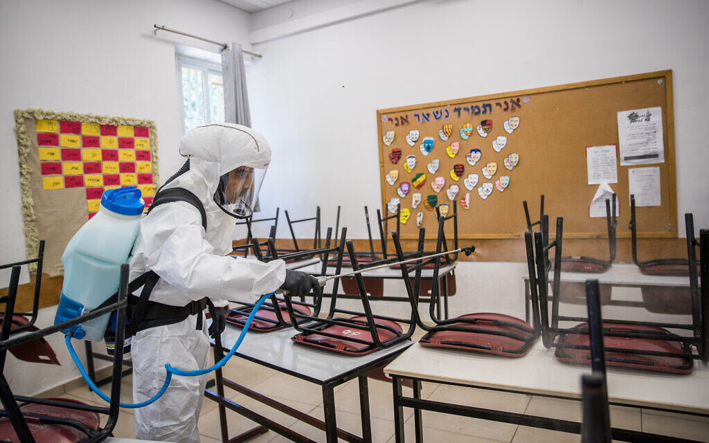 A cleaning worker disinfects a classroom in Jerusalem on June 3, 2020. (Yonatan Sindel/Flash90)