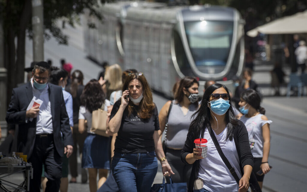 A woman uses a cellphone as people wear face masks for fear of coronavirus in downtown Jerusalem, June 8, 2020. (Olivier Fitoussi/Flash90)