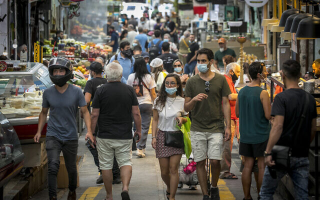 Illustrative: Israelis, wearing facemasks for fear of the coronavirus, shop for groceries at the Mahane Yehuda market in Jerusalem after it reopened according to the new government orders, June 16, 2020. (Olivier Fitoussi/Flash90)
