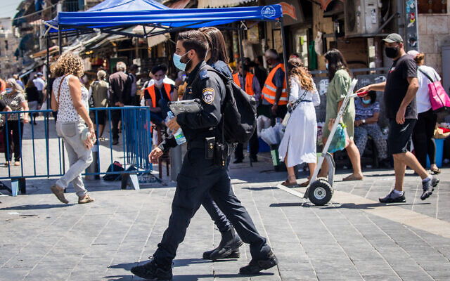 Police officers enforcing social distancing rules patrol outside the Mahane Yehuda market in Jerusalem on June 25, 2020. (Yonatan Sindel/Flash90)