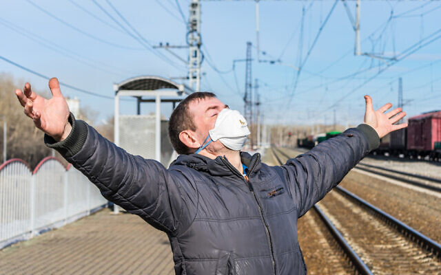 Illustrative image: Joyful man, cured of the disease, standing at a railway station in a medical mask (iStock/Nikolay Chekalin)