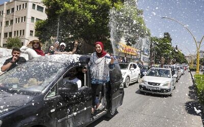Palestinian high school students wave and spray artificial snow from a moving vehicle as they celebrate the announcement of their matriculation exams in Hebron in the West Bank on July 11, 2020. (HAZEM BADER / AFP)