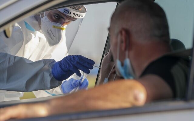 A Magen David Adom paramedic swabs a person for COVID-19 at a drive-thru testing site in the central city of Lod on July 15, 2020. (Ahmad Gharabli/AFP)